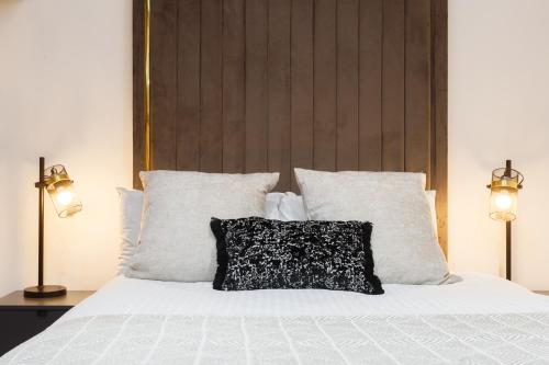 a bed with white sheets and a black and white pillow at Bradford Luxury Central Apartment in Bradford