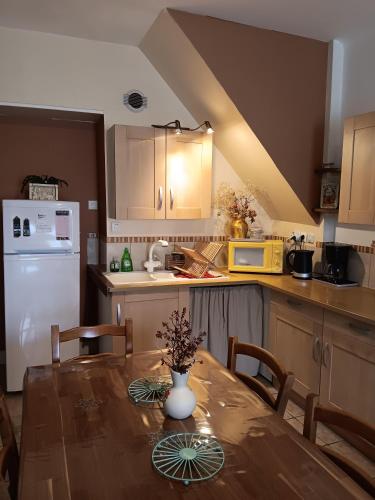 une cuisine avec une table avec un vase de fleurs dessus dans l'établissement maison située à 300 mètres de la thalasso de Pornic et des plages, à Pornic