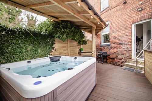 eine Whirlpool-Badewanne auf einer Holzterrasse in der Unterkunft Modern Central Luxury Home with Hot Tub Sauna 12PPL in Sheffield