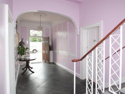 a hallway with pink walls and a staircase with a table at Number 52 Charlotte Street in Glasgow
