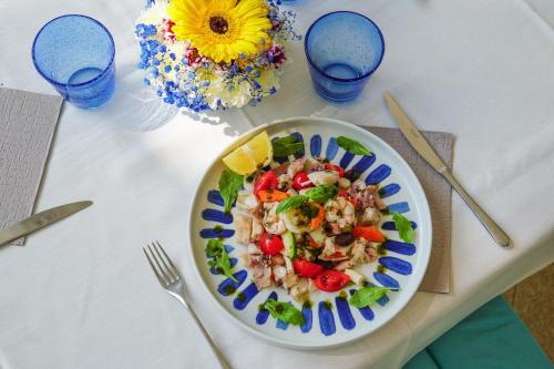 a plate of shrimp salad on a table with blue glasses at Luxury Camp at Union Lido in Cavallino-Treporti