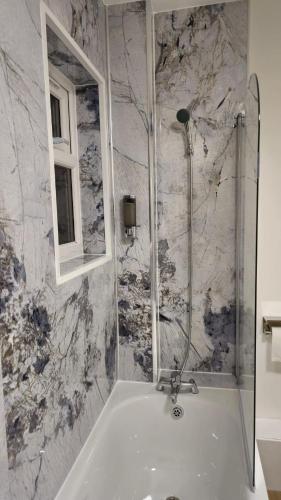 a bathroom with a bath tub and a window at Tyger Inn Derby in Derby