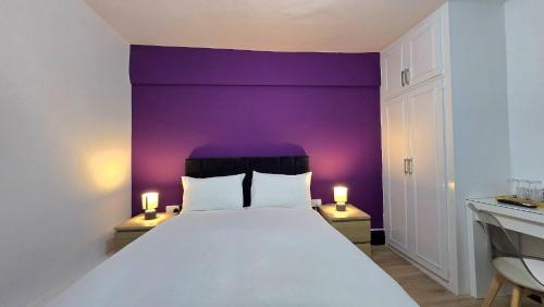 a bedroom with a large bed with a purple wall at Tyger Inn Derby in Derby