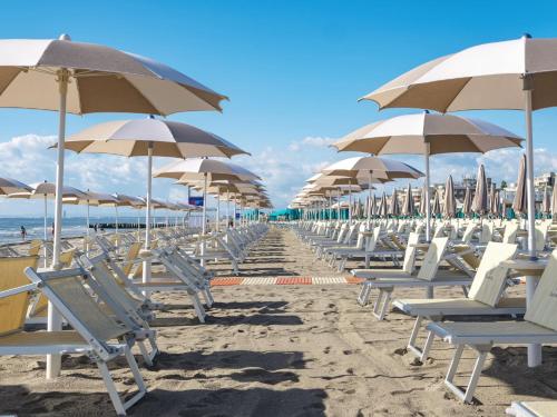 a row of chairs and umbrellas on a beach at Hotiday Milano Marittima Pineta in Milano Marittima
