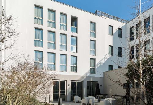 a white building with tables and chairs in front of it at B&B HOTEL Paris Sud Chatenay Malabry in Châtenay-Malabry