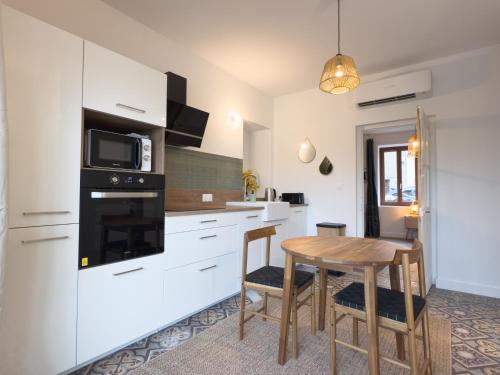 a kitchen with a wooden table and a microwave at Evasion T2 avec terrasse in Saint-Didier-sur-Chalaronne