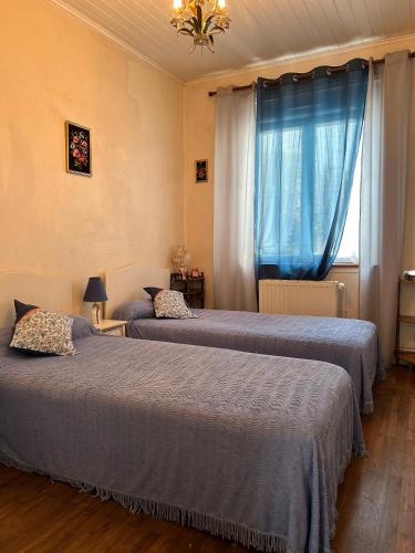 - 2 lits dans une chambre avec des rideaux bleus et une fenêtre dans l'établissement 1 - Maison de pêcheur Pré vert, à Pornic