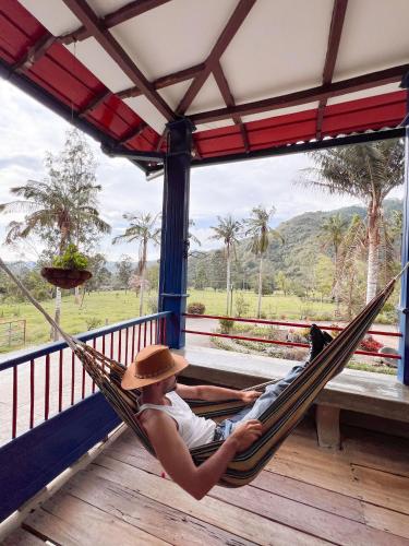 a man laying in a hammock on a porch at Reserva Guadalajara - Cocora Valley in Salento