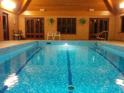 a large swimming pool with blue water in a building at 3 bed countryside cottage with use of private pool in Norwich