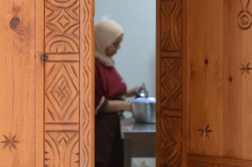 a person standing in a kitchen preparing food at Sunset Surfhouse Morocco in Tamraght Ouzdar