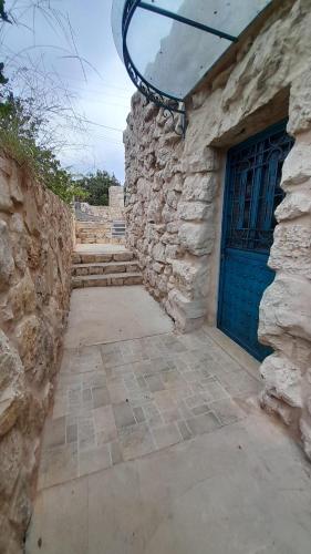 a stone building with a blue door and a stone wall at Bmehrine Village Resort in Jbeil