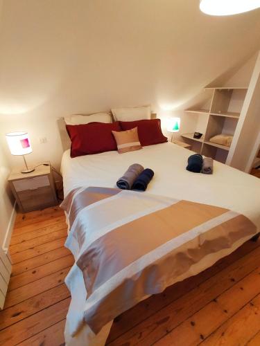 une chambre avec un grand lit blanc avec des oreillers rouges dans l'établissement Magnifique villa face à la plage de Pors Peron, à Beuzec-Cap-Sizun