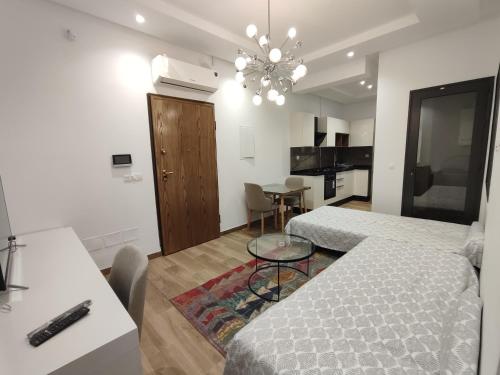 Un dormitorio con dos camas y una mesa y una cocina. en Coquet appartement avec piscine à 10min de l'aéroport Tunis - family only, en La Soukra
