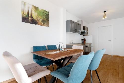 a dining room with a wooden table and blue chairs at White House Apartments in Kappel-Grafenhausen