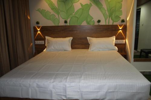 a bedroom with a large bed with two white pillows at Wood Castle Munnar in Munnar