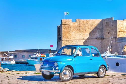 an old blue car parked in front of a harbor at Casa GioNi’ in Monopoli