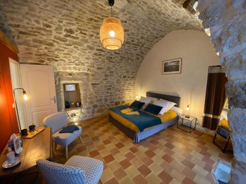 a bedroom with a bed and chairs in a room at Les Caselles, Gîte et Chambre d'hôtes in Saint-Beauzély