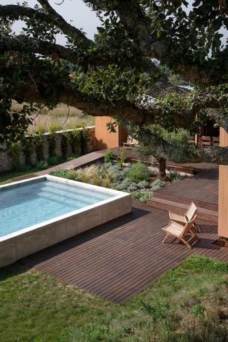 a wooden deck with a swimming pool and a bench and a chair at Wood Mood Lodges in Caminha