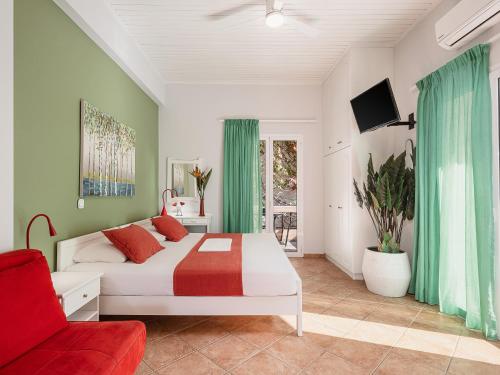 a bedroom with a white bed and a red chair at Elena Seafront Luxury Apartments in Almirida