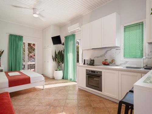 a kitchen with white cabinets and green curtains at Elena Seafront Luxury Apartments in Almirida