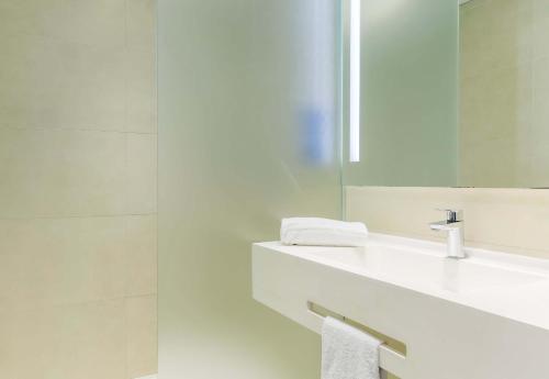 a white bathroom with a sink and a mirror at B&B HOTEL Longwy Porte du Luxembourg in Longwy