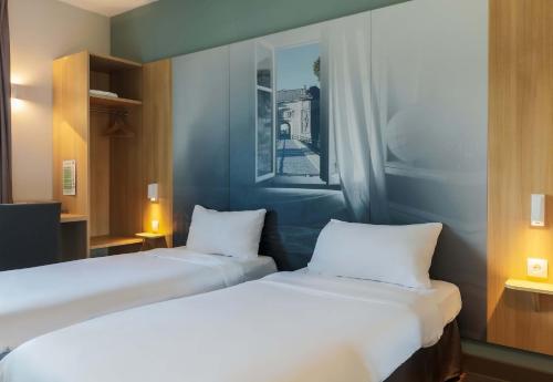 two beds sitting next to each other in a room at B&B HOTEL Longwy Porte du Luxembourg in Longwy
