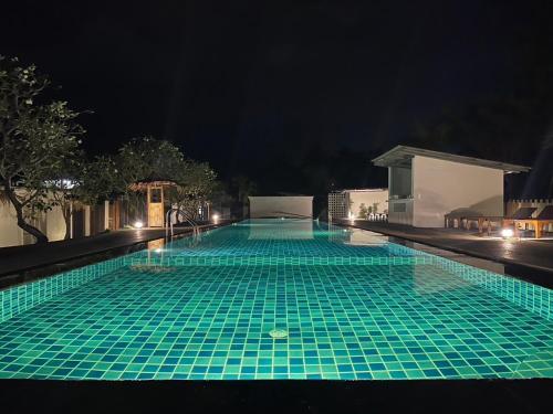 a swimming pool at night with green tiles at Sea Escapes Resort in Thongsala