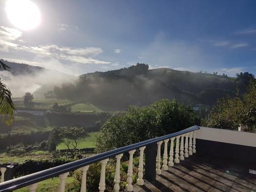 a balcony with a view of a mountain with the sun at Villa Magia Verde in Furnas