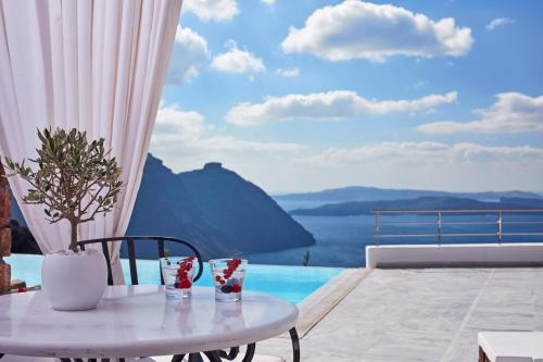 a table and chairs with a view of the water at San Antonio - Small Luxury Hotels of the World in Imerovigli