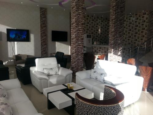 un soggiorno con 2 divani bianchi e una TV di Lara Al Jawf Hotel Apartments a Sakakah