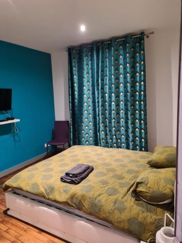 une chambre avec un lit et un mur bleu dans l'établissement Maison en centre ville, à Cormeilles-en-Parisis