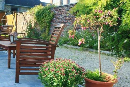 a wooden bench sitting in a garden with flowers at La brasserie in Chooz