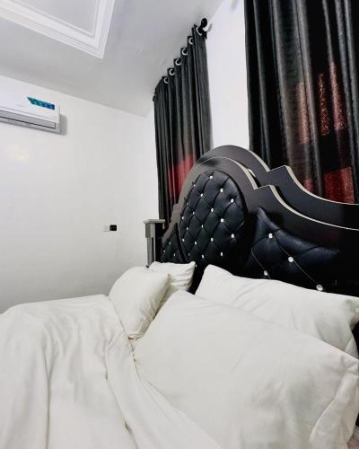 two beds with white sheets and a black headboard at Comfortable 1 bedroom Apartment in Garki