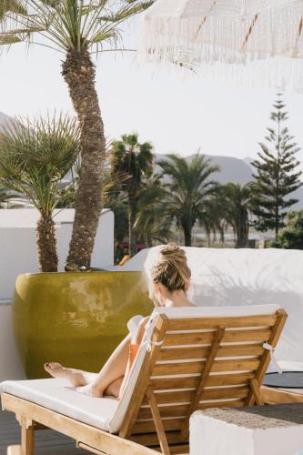 a woman sitting in a chair next to a palm tree at Dreamsea Boutique Experience in Moya