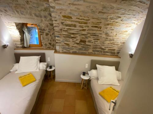 two beds in a room with a stone wall at Les Caselles, Gîte et Chambre d'hôtes in Saint-Beauzély