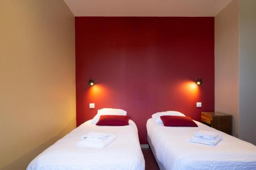 two beds in a room with red walls at Logis Hôtel Restaurant Le Louvre in Sault-de-Vaucluse