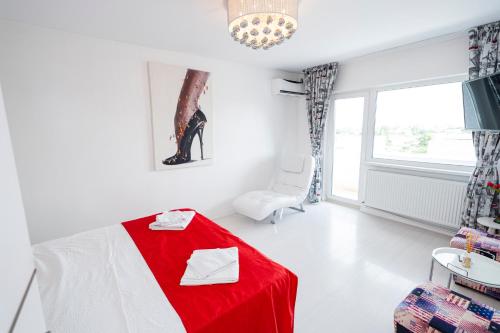 a white room with a red bed and a chair at Panorama Suite in Galaţi