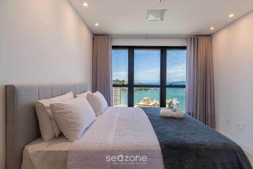 a bedroom with a large bed with a large window at MHF II - Apts Variados em Prédio com Vista para o Mar em Itapema in Itapema