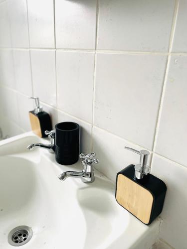 a bathroom sink with two cups and a soap dispenser at Atlantis Luxe escape Unit 25 in Uvongo Beach