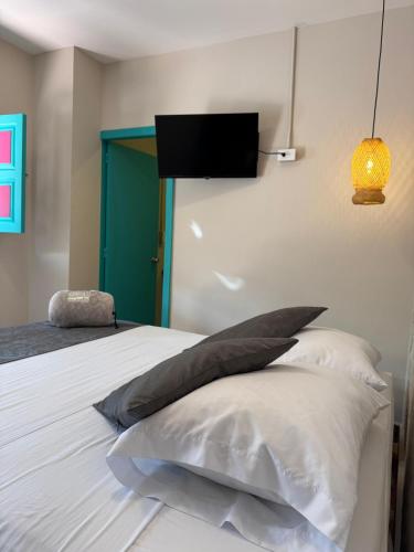 a bedroom with a bed with pillows and a tv on the wall at CASA HOTEL LAS HORTENSIAS in Jardin