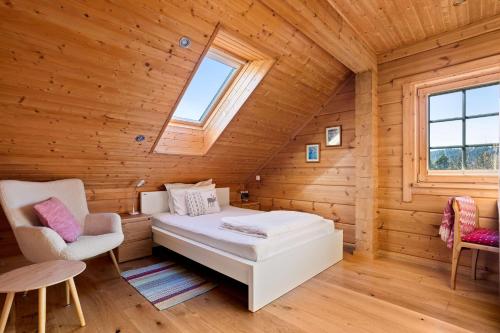 a bedroom in a log cabin with a bed and two chairs at Wellness Chalet close to Ljubljana in Rakitna