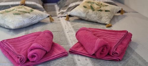 two pink towels sitting on a bed with pillows at Naturiste Port Nature in Cap d'Agde