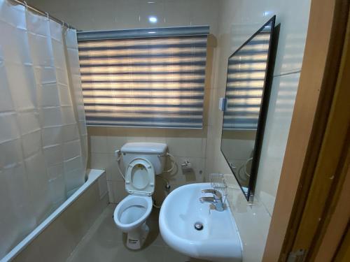 ein Badezimmer mit Toilette und Waschbecken in der Unterkunft Tobas Apartments in Uyo