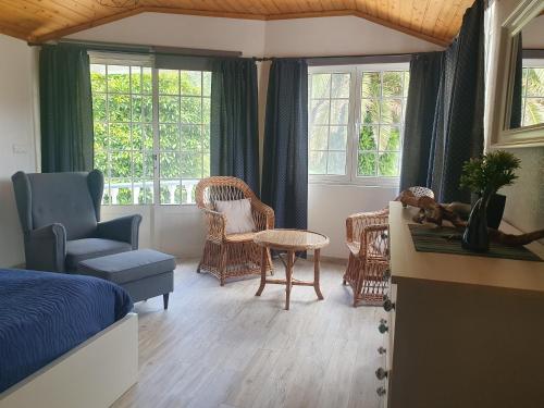 a bedroom with a bed and chairs and windows at Villa Magia Verde in Furnas