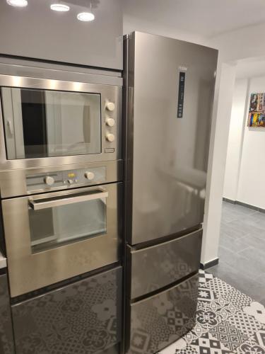 La cuisine est équipée d'un four et d'un réfrigérateur en acier inoxydable. dans l'établissement Maison en centre ville, à Cormeilles-en-Parisis