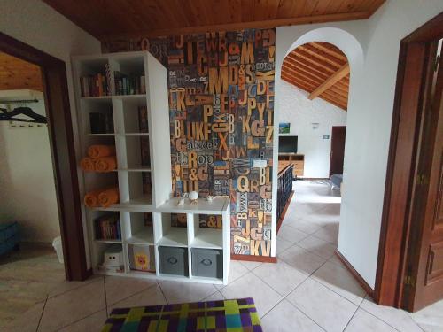 a room with a book shelf and a wall withwords at Villa Magia Verde in Furnas
