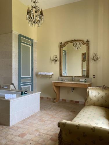 a bathroom with a sink and a mirror and a couch at Château de la Ferrière in Bayeux