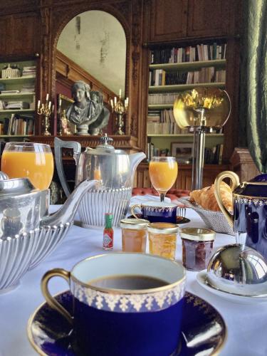 a table with a cup of coffee and a tea pot at Château de la Ferrière in Bayeux