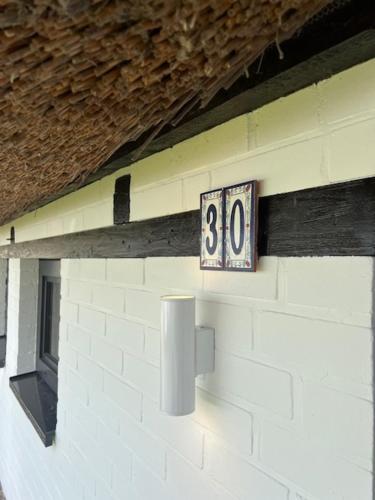 a clock on the side of a building at Gemütliches Reetdachhaus in Oesterdeichstrich