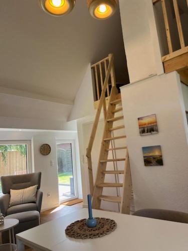 a living room with a staircase and a vase on a table at Gemütliches Reetdachhaus in Oesterdeichstrich